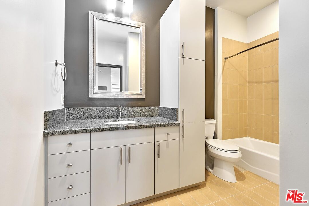 3810 Wilshire Boulevard, Unit 404 Los Angeles, CA 90010 - Photo 17 of 43 a bathroom with a granite countertop sink a toilet and a mirror