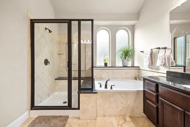 a spacious bathroom with a tub a mirror and a shower