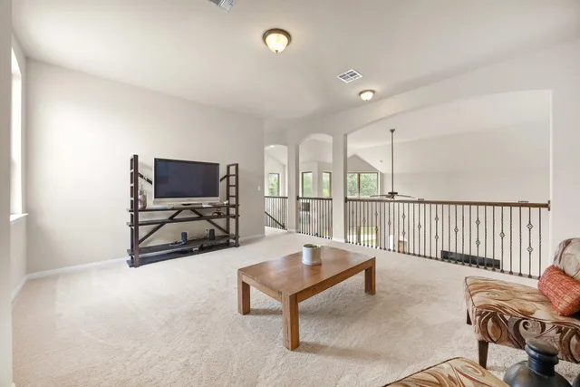 a living room with furniture a flat screen tv and floor to ceiling window