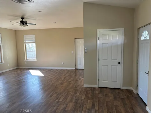 an empty room with wooden floor cabinet and windows