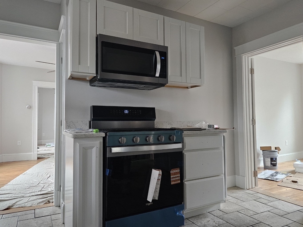 9 Victoria Street, Unit 1 Lowell, MA 01851 - Photo 2 of 8 a kitchen with a stove and a microwave