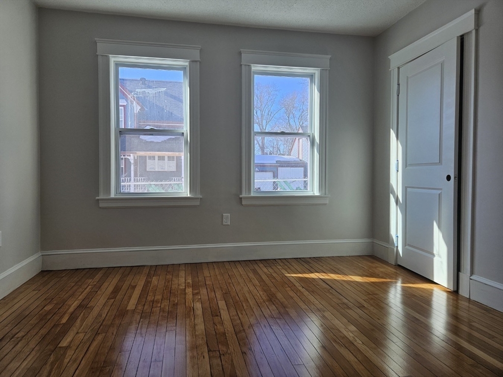 9 Victoria Street, Unit 1 Lowell, MA 01851 - Photo 5 of 8 an empty room with wooden floor and windows