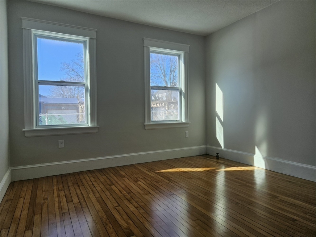 9 Victoria Street, Unit 1 Lowell, MA 01851 - Photo 6 of 8 an empty room with wooden floor and windows