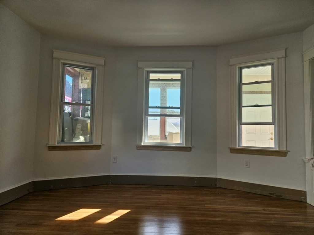 9 Victoria Street, Unit 1 Lowell, MA 01851 - Photo 7 of 8 an empty room with wooden floor and windows