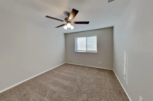 an empty room with closet and a ceiling fan