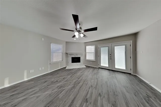 a view of an empty room with wooden floor and a fireplace