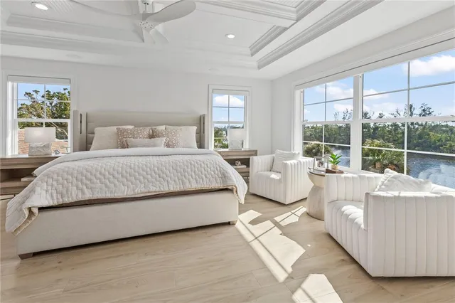 a living room with couches a flat screen tv and a large window with kitchen view