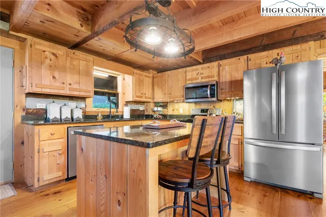 a kitchen with stainless steel appliances granite countertop a table chairs refrigerator and microwave
