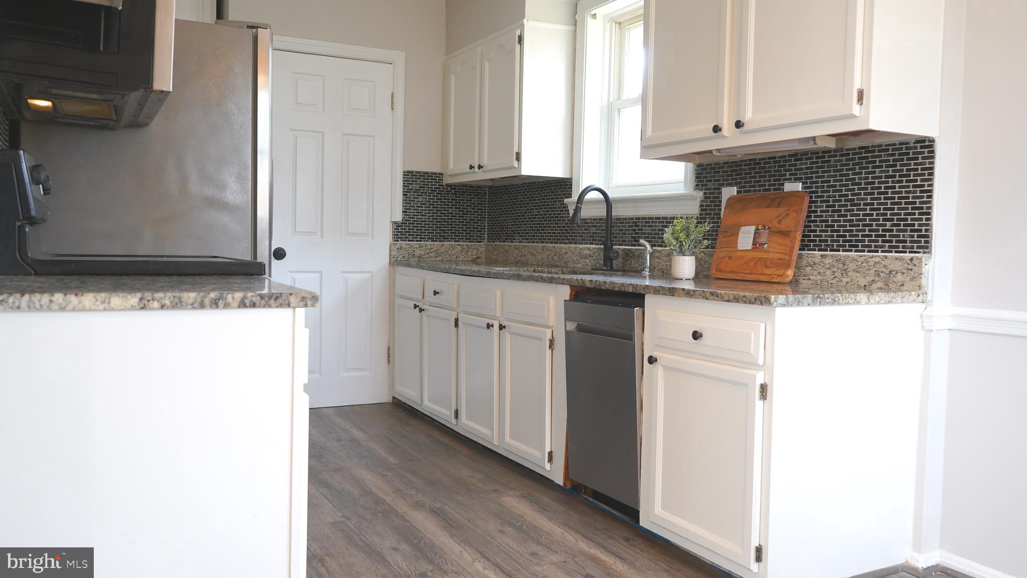 9300 Worrell Avenue Lanham, MD 20706 - Photo 6 of 63 a kitchen with granite countertop a sink and a stove with wooden floor