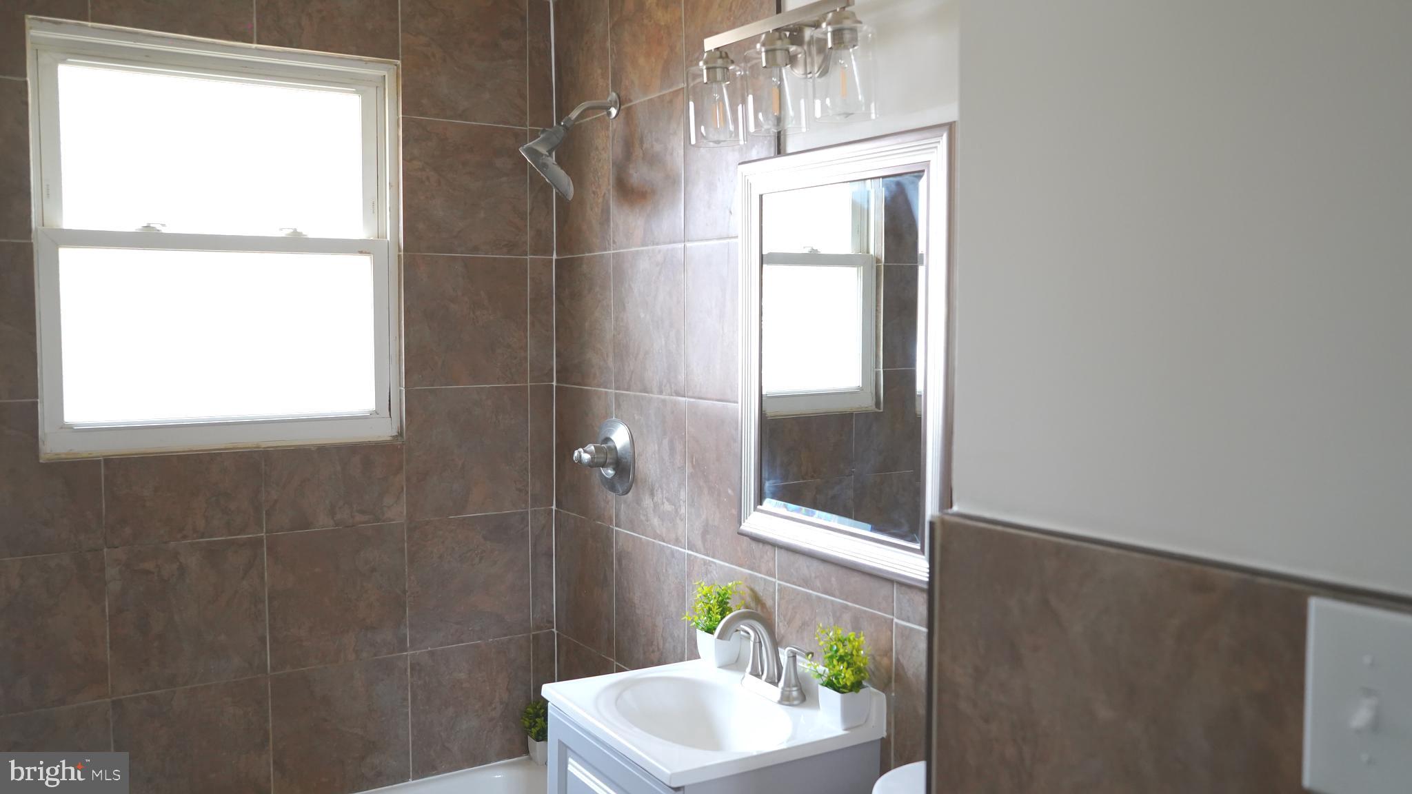 9300 Worrell Avenue Lanham, MD 20706 - Photo 10 of 63 a bathroom with a window a sink and a mirror