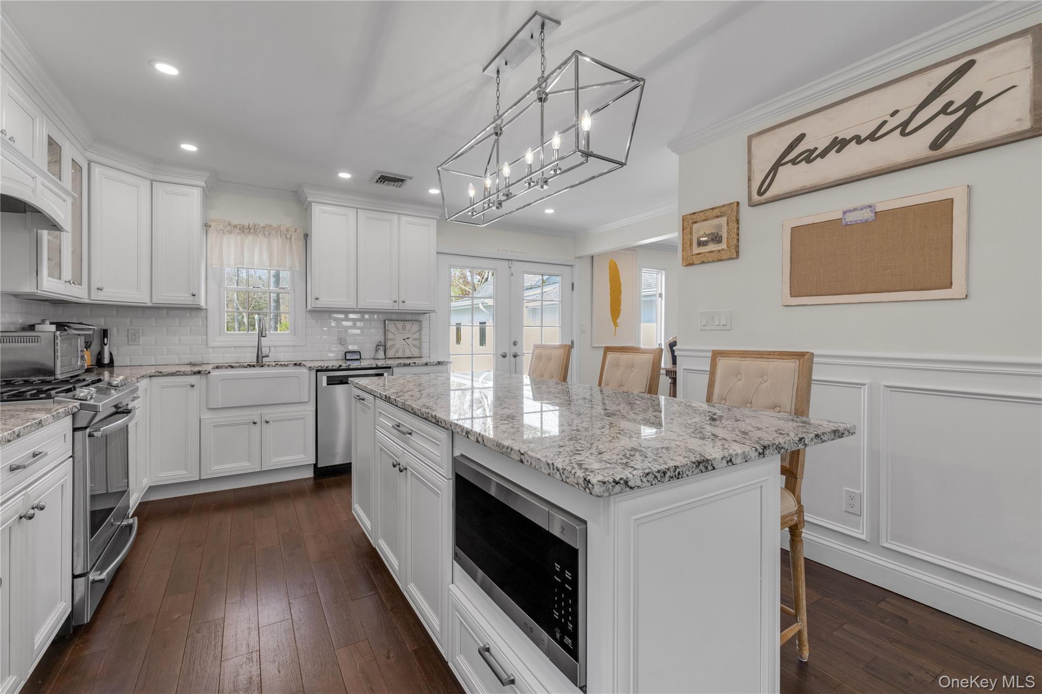 23 Grove Street Cold Spring Harbor, NY 11724 - Photo 8 of 21 a kitchen with stainless steel appliances granite countertop a sink dishwasher a stove and white cabinets with wooden floor