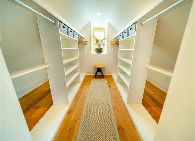 a view of walk in closet with wooden floor