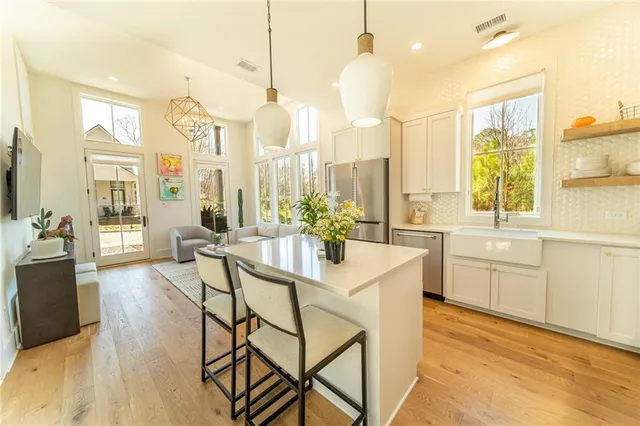 a kitchen with stainless steel appliances kitchen island granite countertop a table chairs sink and cabinets