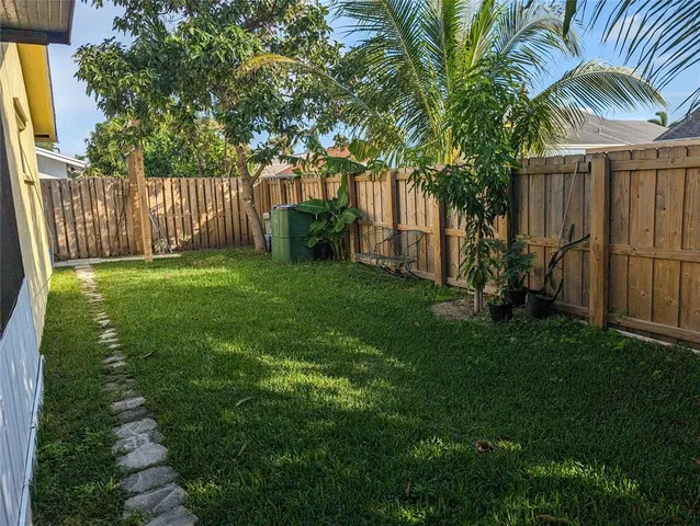 a view of a backyard with wooden fence and a large tree