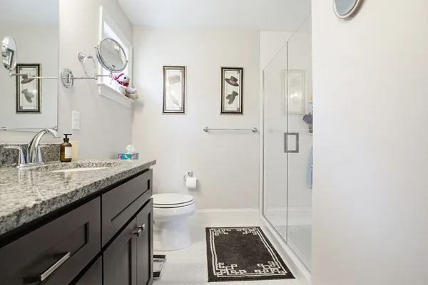a bathroom with a granite countertop sink a toilet and a mirror