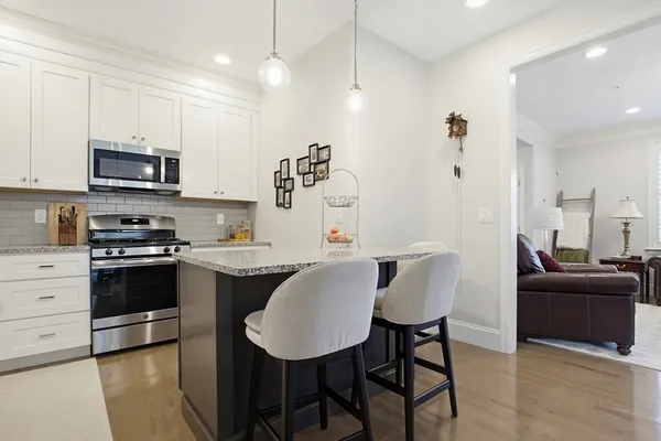 a kitchen with stainless steel appliances granite countertop a stove a sink a microwave a dining table and chairs