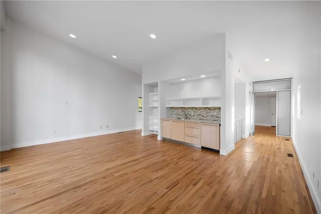 a big room with wooden floor and a kitchen