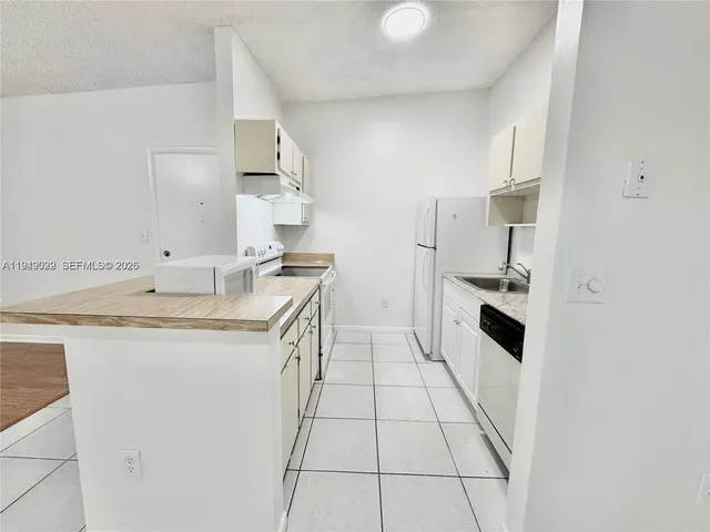 a kitchen with granite countertop a sink stove and refrigerator