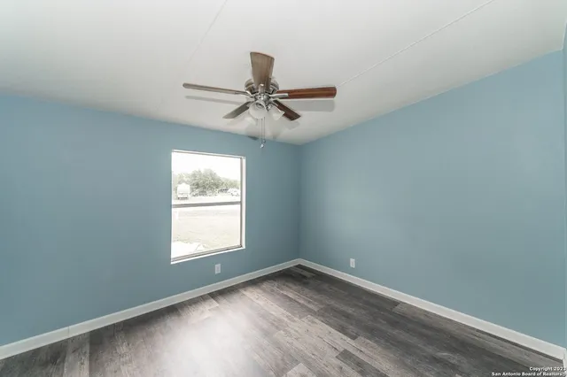an empty room with a window and a fan
