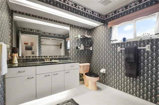 a spacious bathroom with a toilet a sink and mirror