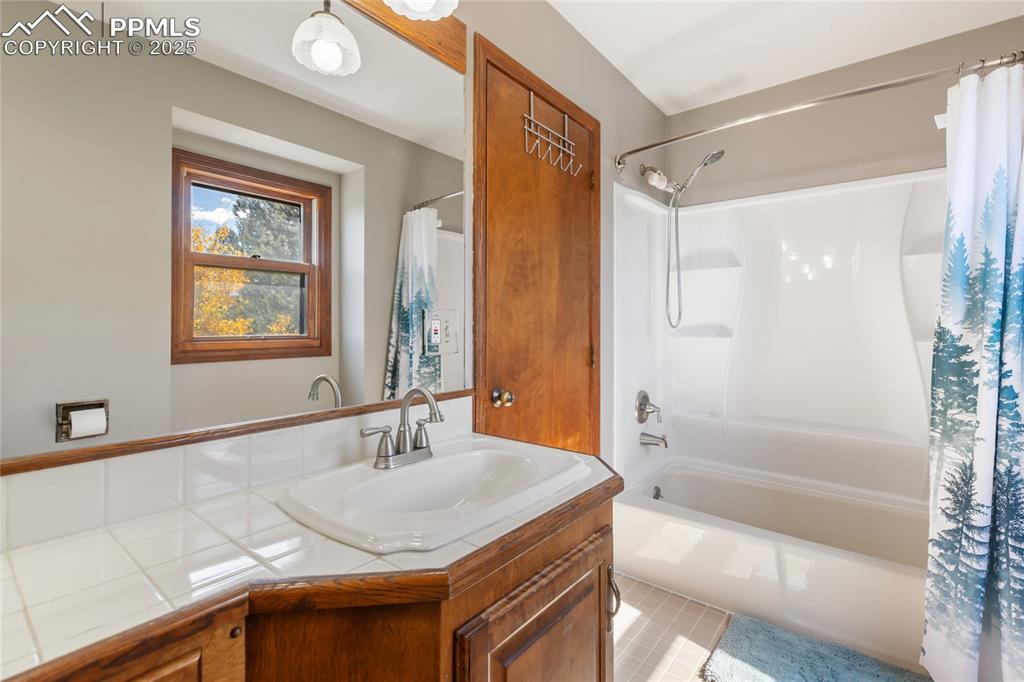 356 Spring Valley Drive Divide, CO 80814 - Photo 31 of 50 a bathroom with a granite countertop sink a mirror a bathtub and shower