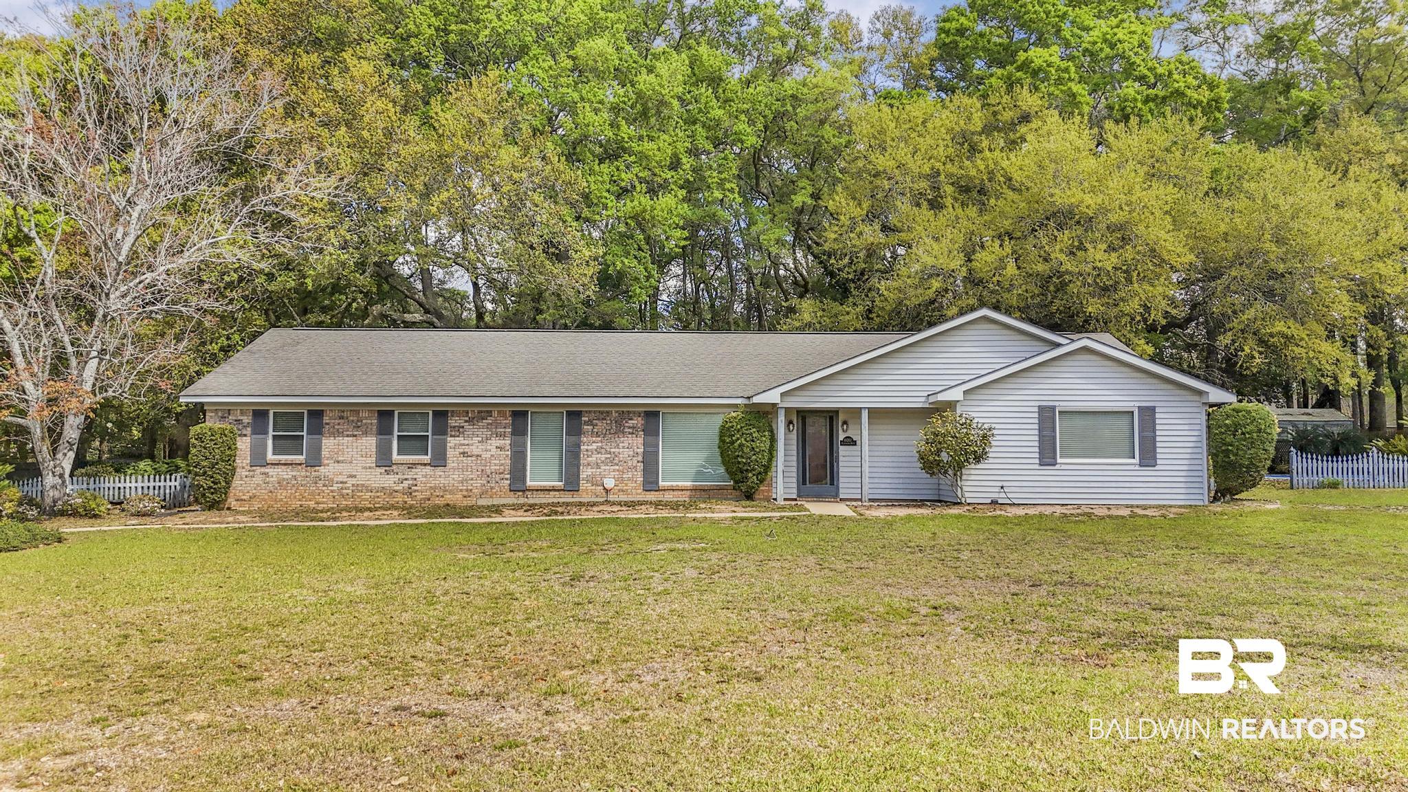 10207 Plantation Drive Daphne, AL 36526 - Photo 1 of 48 Ranch-style home with brick siding, roof with shingles, and view of wooded area
