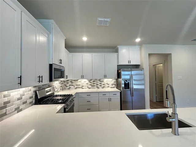 a kitchen with stainless steel appliances kitchen island granite countertop a refrigerator and a stove top oven