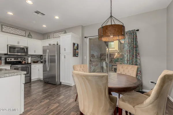 a kitchen with stainless steel appliances granite countertop a refrigerator a stove a microwave oven a sink with a dining table and chairs