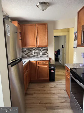 a kitchen with stainless steel appliances granite countertop a refrigerator a stove and a wooden floors