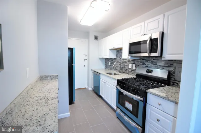 a kitchen with stainless steel appliances granite countertop a stove top oven microwave and refrigerator
