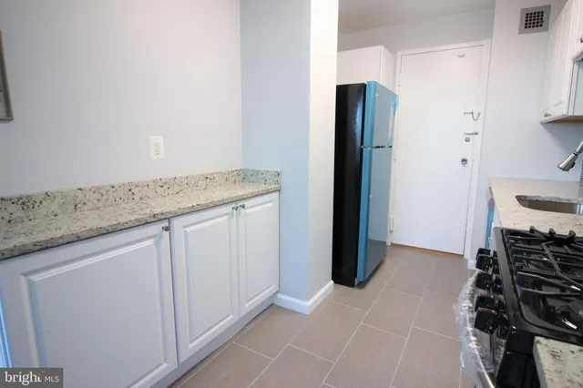 a kitchen with granite countertop a sink and a refrigerator