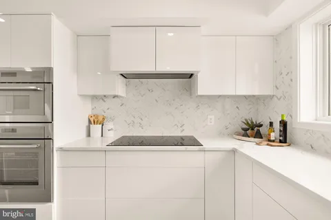 a kitchen with stainless steel appliances granite countertop a sink dishwasher a refrigerator a stove and white cabinets with wooden floor