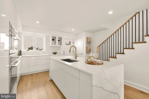 a kitchen with white cabinets and sink