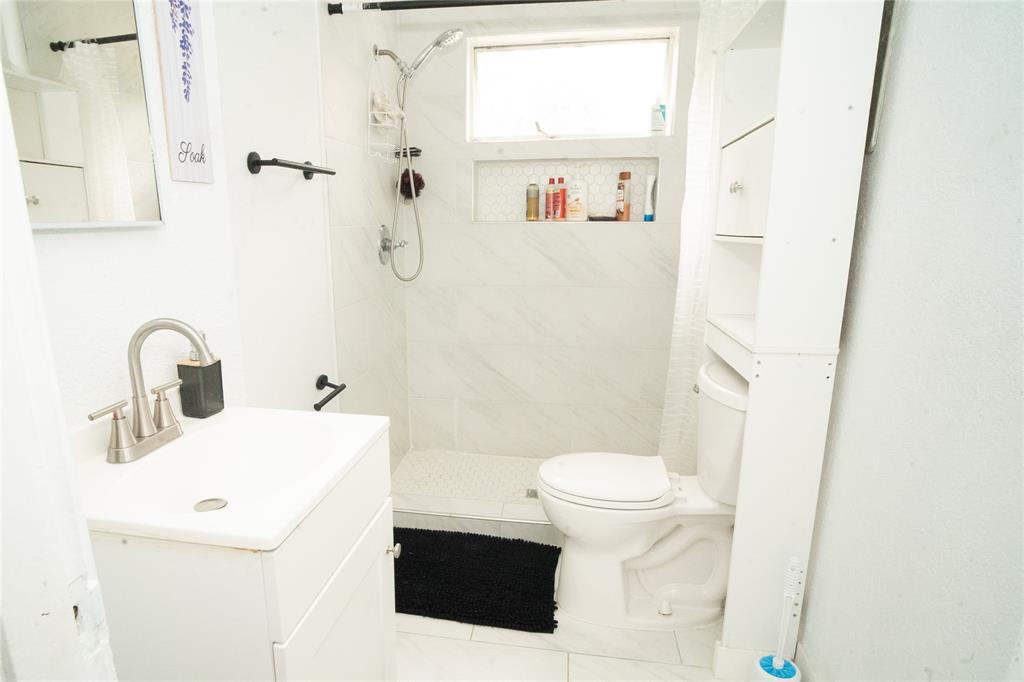 2136 Ridgeway Street Arlington, TX 76010 - Photo 11 of 32 a bathroom with a sink a toilet and shower curtain