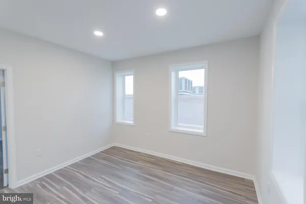 an empty room with wooden floor and windows