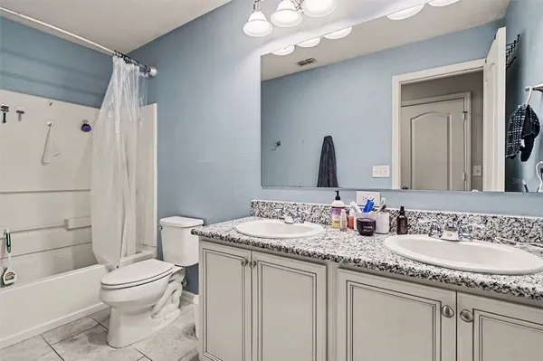 a bathroom with a granite countertop sink a toilet a mirror a vanity and shower