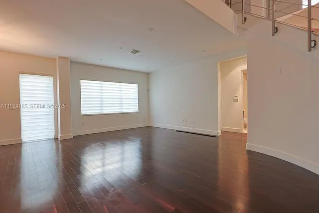 a view of an empty room with wooden floor and window