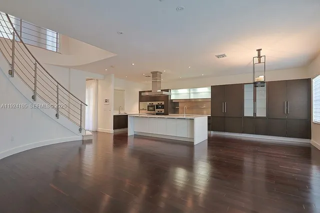 an empty room with wooden floor closet and windows