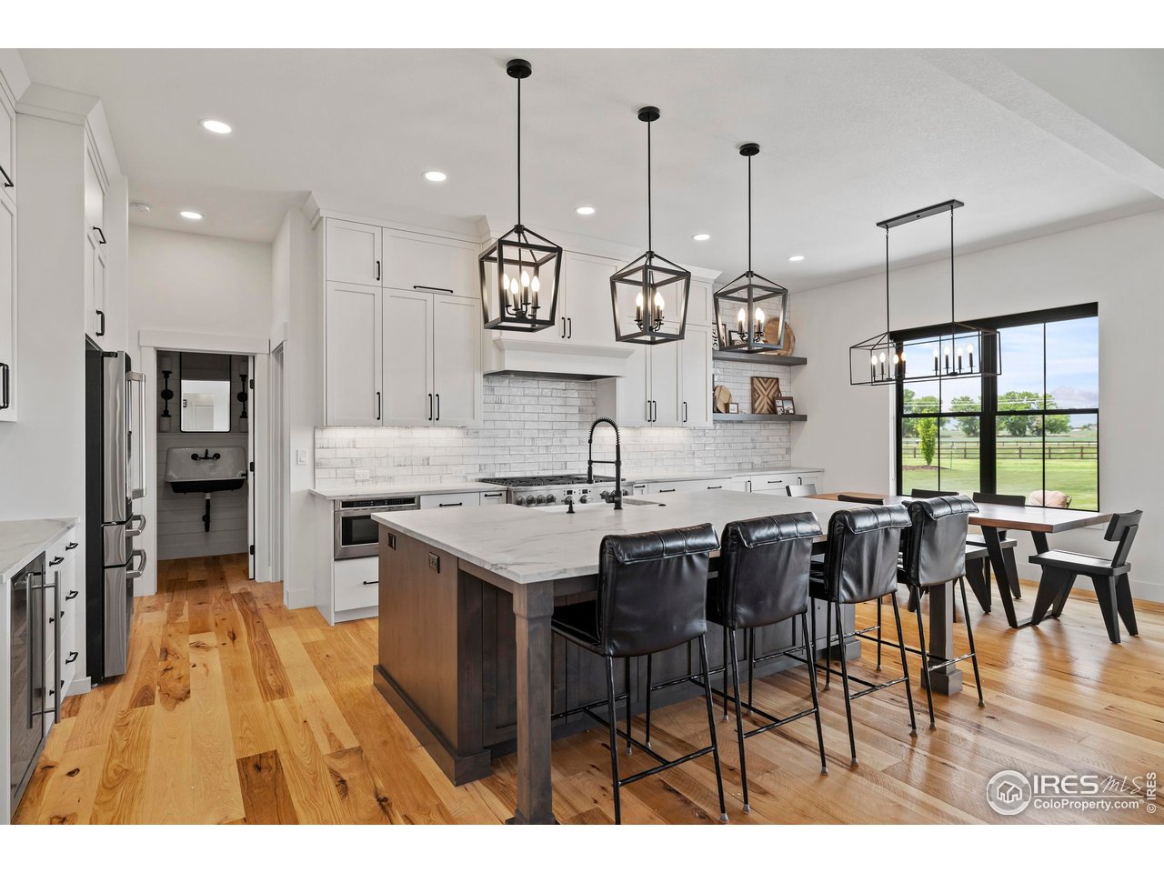 37179 Soaring Eagle Circle Severance, CO 80550 - Photo 11 of 40 a kitchen with stainless steel appliances kitchen island granite countertop a stove a sink a dining table and chairs with wooden floor