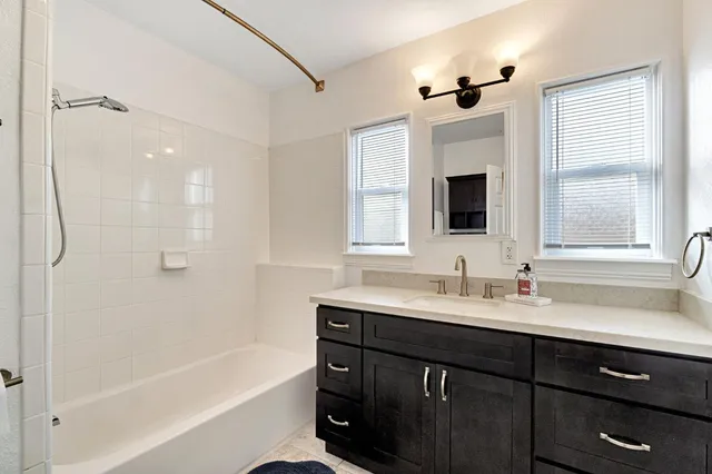 a bathroom with a tub a sink double vanity and a mirror