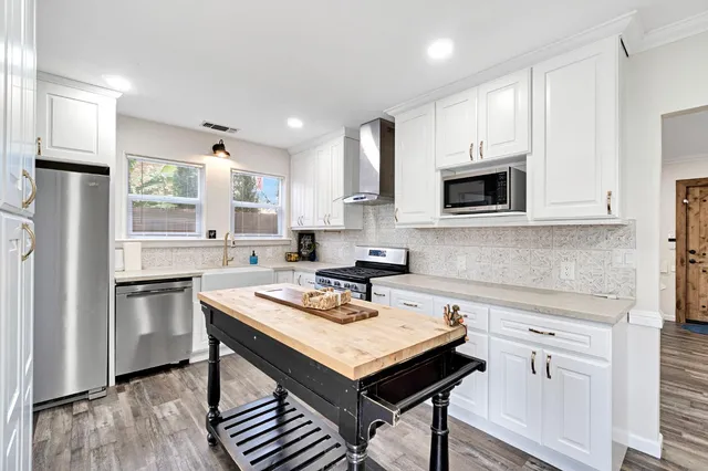 a kitchen with stainless steel appliances a stove a sink a microwave a refrigerator and cabinets