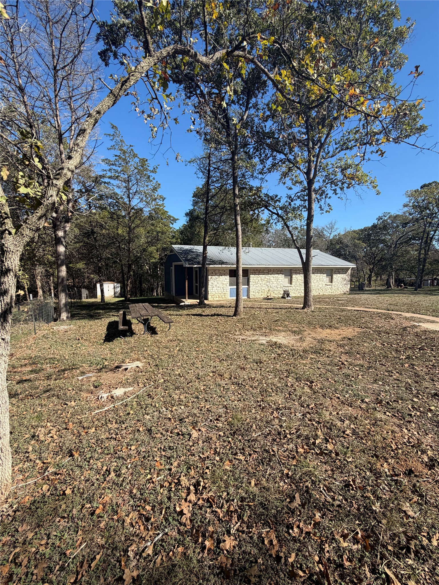 214 The Forest Road Dale, TX 78616 - Photo 3 of 18 A charming single-story residence nestled among mature trees, boasting a combination of stone and siding.