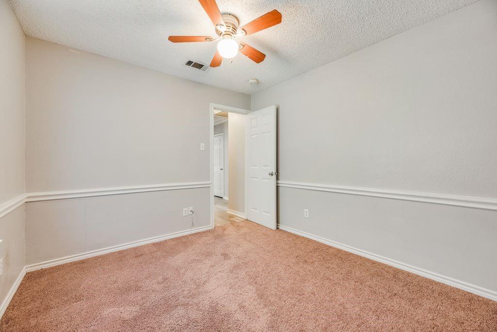 5610 Eagle Rock Road Arlington, TX 76017 - Photo 16 of 33 Carpeted room featuring a ceiling fan with wood-finish blades, white wall trim, and a paneled interior door