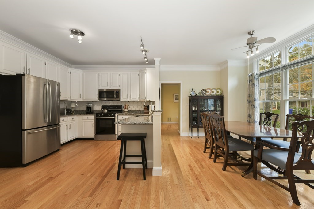 7 Moore Circle, Unit 7 Bedford, MA 01730 - Photo 11 of 27 a kitchen with stainless steel appliances a refrigerator a stove top oven a sink dishwasher a dining table and chairs with wooden floor