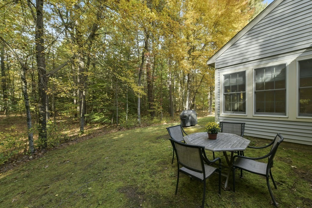 7 Moore Circle, Unit 7 Bedford, MA 01730 - Photo 24 of 27 a view of a backyard with table and chairs and wooden fence