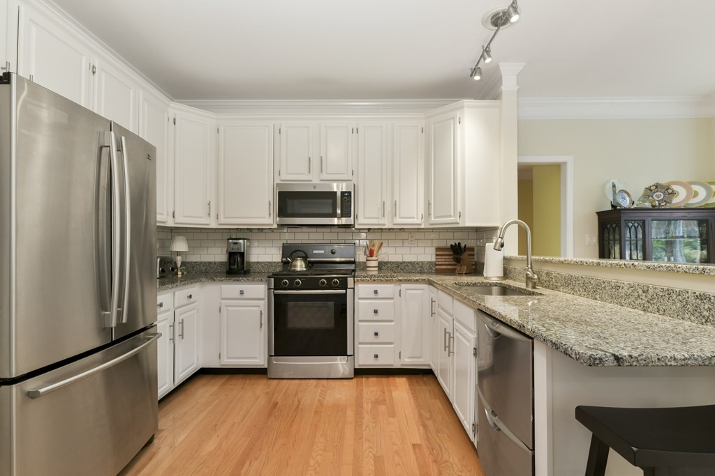 7 Moore Circle, Unit 7 Bedford, MA 01730 - Photo 10 of 27 a kitchen with stainless steel appliances granite countertop a sink stove microwave and refrigerator