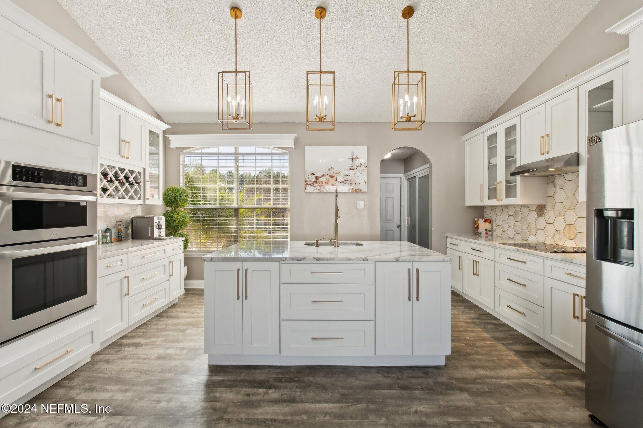 a kitchen with stainless steel appliances kitchen island granite countertop a stove and white cabinets