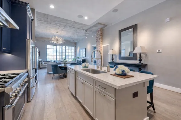 a kitchen with stainless steel appliances granite countertop a refrigerator a sink dishwasher a stove with wooden cabinets and floor