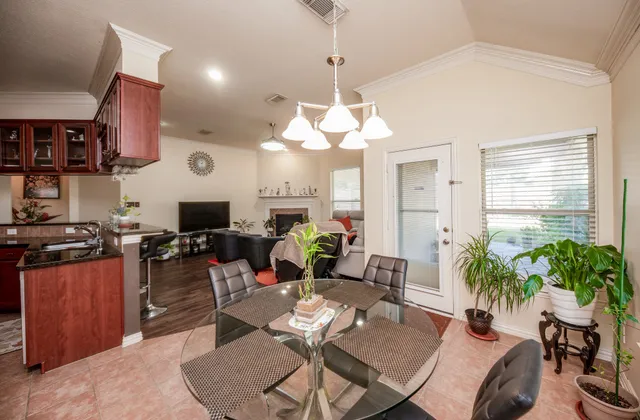 a living room with lots of furniture dining table a chandelier a large window and potted plant