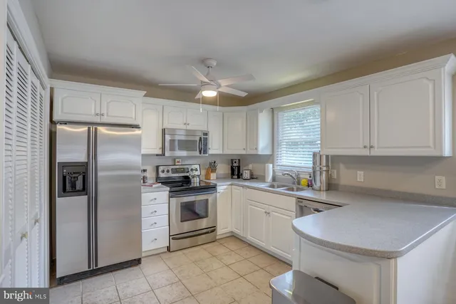 a kitchen with stainless steel appliances a sink a stove a refrigerator cabinets and a window